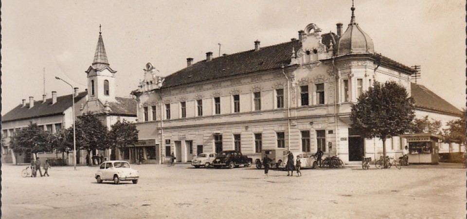 Na staroj fotografiji s druge polovine 20. veka vidi se centar Stare Pazove, automobili, hotel Srem, ljudi, filijalna katolička crkva  itd.
