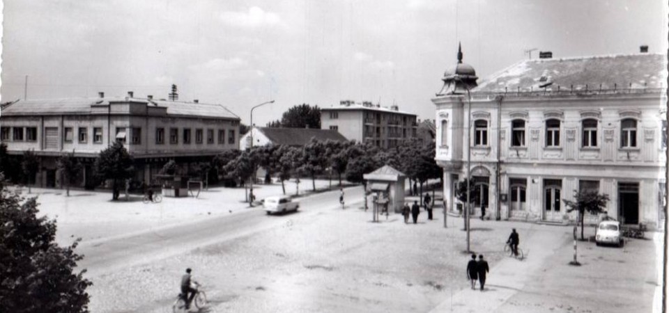 Na staroj fotografiji s druge polovine 20. veka vidi se centar Stare Pazove, štedionica iz 1905.god., kiosk na centru, ljudi,biciklista, automobili, sa leve strane je zgrada firme Cetrosrem,drvored i stambene zgrade.