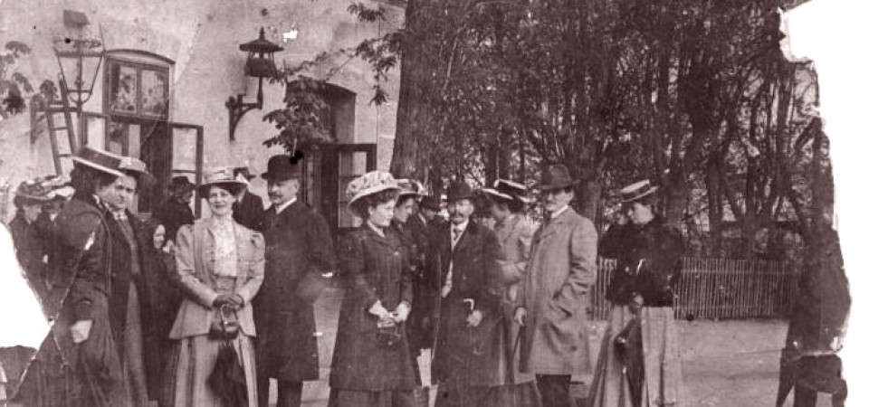 Na staroj fotografiji s druge polovine 19. veka vide se ljudi koji čekaju voz na železničkoj stanici u Staroj Pazovi i zgrada stanice.